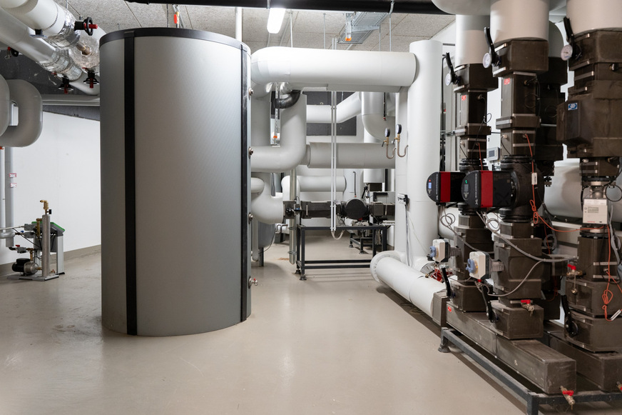 Drei der sechs Wärmepumpen sowie einer der beiden 2.000-Liter-Pufferspeicher wurden vom restlichen Heizsystem entkoppelt und beheizen einen angrenzenden Altbau der EVM Berlin.