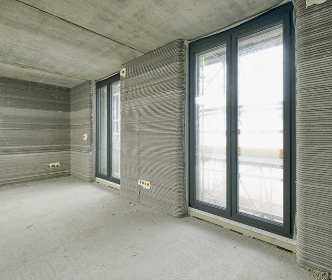 Kantige Kunststoffprofile zwischen runden Beton­wülsten – raumhohe Comfort MD 82-Elemente von Gugelfuss verschließen die Öffnungen in dem größten gedruckten Wohnhaus Europas.