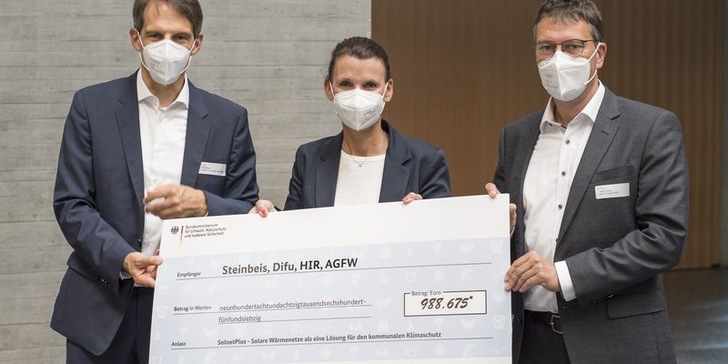 Die Parlamentarische Staatssekretärin Rita Schwarzelühr-Sutter übergibt den Förderbescheid an die Projektpartner, darunter Dirk Mangold, Leiter Steinbeis Solites (links) und Dr. Heiko Huther, Bereichsleiter Forschung & Entwicklung AGFW.