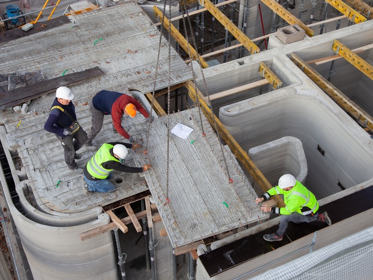 Bauarbeiter montieren die Fertigteildeckenelemente mit Flächenheizung für das Beckumer Einfamilienhaus aus dem Drucker. - © Aquatherm
