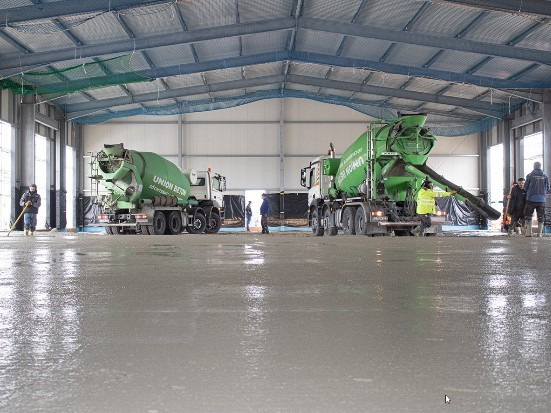 Auf der Testbaustelle bei Zosseder in Großkarolinenfeld bringen Transportbeton-Mischfahrzeuge von Union Beton den Estrich aus Recycling-Beton aus.
