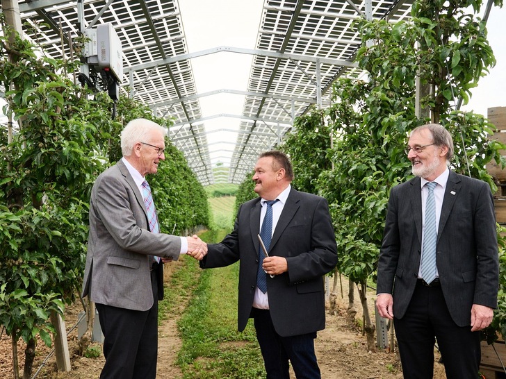 Baden-Württembergs Ministerpräsident Winfried Kretschmann (links) gratuliert Landwirt Hubert Bernhard und Fraunhofer ISE-Leiter Andreas Bett zur Einweihung einer Agri-Photovoltaikanlage in Kressbronn.