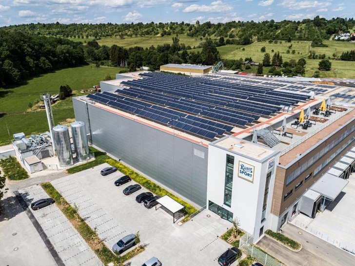 Die derzeit größte Solarthermie-Dachanlage in Deutschland erzeugt auf einem Lagergebäude von Ritter Sport in Dettenhausen umweltfreundliche Energie für ein Wärmenetz. Daneben steht die neu erbaute Energiezentrale. - © swt/Marquardt
