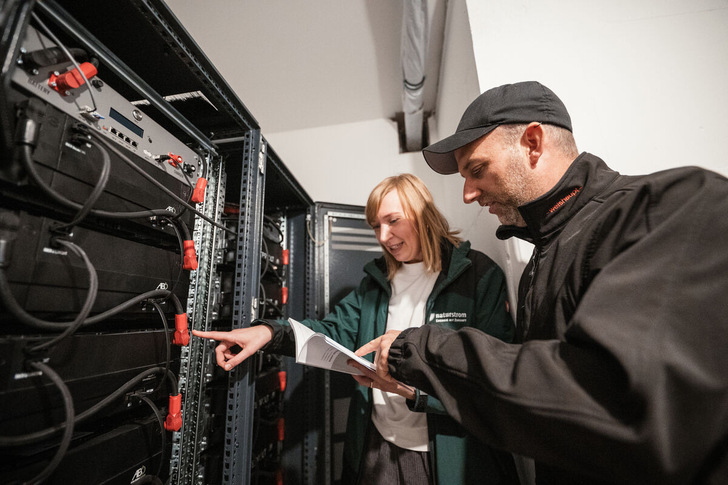 Naturstrom-Mitarbeiterin Melanie Kühl und Gordon Grundorf von S|2 Gebäudetechnik GmbH begutachten  in der Energiezentrale die Batteriespeicher des Forschungsprojekts MELANI. - © Simon Thon
