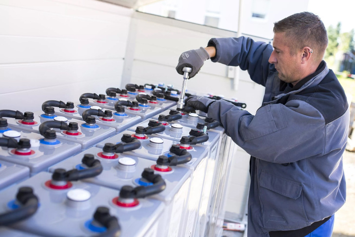 Ein Fachmann installiert einen großen Blei-Gel-Speicher in einem energieautarken Einfamilienhaus in Freiberg.