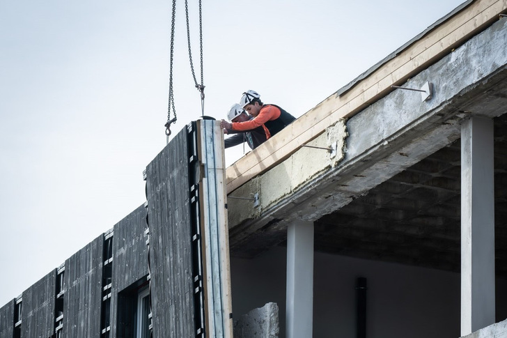 Arbeiter montieren die vorgefertigten Fassadenelemente an der Feuerwache in Charlottenburg-Nord.