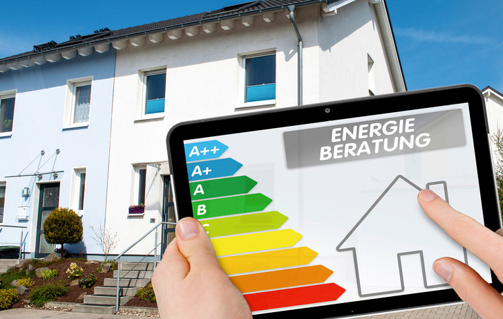 Person hält ein Tablet mit einem Energieeffizienzdiagramm vor einem modernen weißen Haus. - © Bild: Stockwerk-Fotodesign - stock.adobe.com