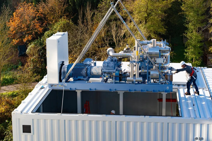 Eine Großwärmepumpe wird in ein Produktionsgebäude der Schokoladenfarik Alfred Ritter abgelassen.