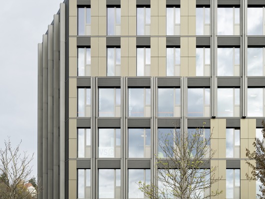 Kopfbau im Areal des ehemaligen Tübinger Güterbahnhofs: Die pulverbeschichteten Aluminiumbleche der Vorhangfassade orientieren sich in Farbe und Materialität an den siebbedruckten Dünnschichtmodulen. Ein optischer Unterschied ist nicht auszumachen.