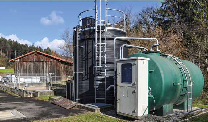 Klärgas-KWK in Bergatreute: Im Winter benötigt ein im Gebäude integrierter Faulbehälter sehr viel Heizwärme, um die Gärung in Gang zu halten. Der Energieinhalt des eingeschwemmten Abwassers reicht dazu nicht aus. Deshalb wird dem Klärschlamm von Fall zu Fall ein Co-Substrat aus dem grünen Behälter beigemischt, um das Klärgasvolumen zu erhöhen. Der schwarze Fällmittelbehälter links daneben bevorratet das für die Phosphor-Elimination nötige Fällmittel. Gebaut hat das KWK-System die Firma Enerquinn aus dem oberschwäbischen Weingarten.