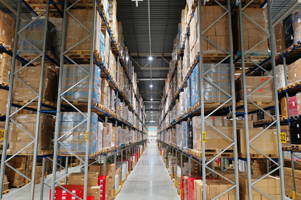 In einem Regallager ist die vertikale Beleuchtungsstärke wichtig. Denn nur wenn die Helligkeit ausreicht, sind Beschriftungen auf Waren und an den Regalen mühelos zu lesen. Die Hallenhöhe entscheidet über die Wahl der Leuchten: Bis sechs Meter Höhe werden eher LED-Lichtbandsysteme und ab sechs Metern auch LED-Hallenleuchten eingesetzt.