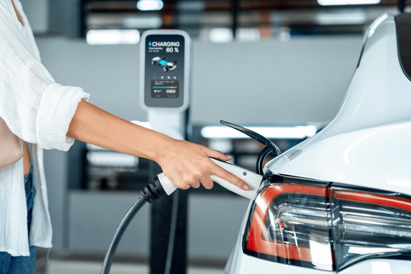 Person, die ein weißes Elektroauto an einer Ladestation auflädt, bei der der Akku zu 80 % angezeigt wird. - © Summit Art Creations - stock.adobe.com