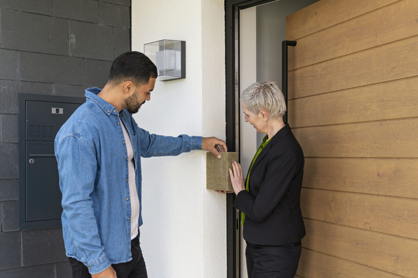 Zwei Personen untersuchen eine Probe der Außenwanddämmung neben einer Tür. - © Zukunft Altbau