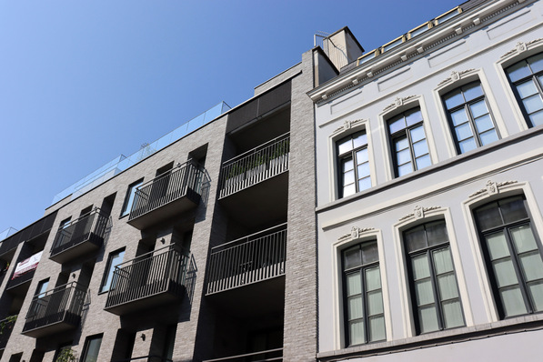 Sicht auf ein modernes Wohngebäude mit integrierter Smart-Building-Technologie und intelligentem Energiemanagementsystem, umgeben von traditioneller Architektur, symbolisiert die Integration fortschrittlicher Gebäudetechnik in bestehende Stadtlandschaften. - © finecki - stock.adobe.com