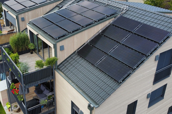 Modernes Haus mit Sonnenkollektoren auf dem Dach und bepflanzten Balkonen. - © Consolar