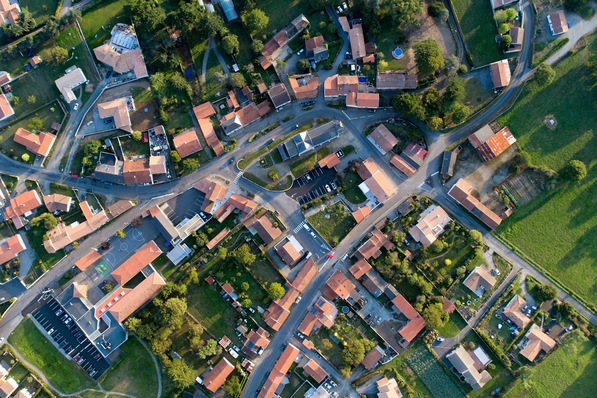 Luftaufnahme eines Wohnviertels mit Häusern, Straßen und Grünflächen mit roten Dächern. - © altitudedrone - stock.adobe.com