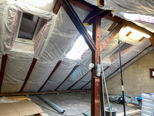 Dachgeschoss eines Hauses aus den 1920ern, im Ausbau befindlich: Die Bahnen, die die Luftdichtheit herstellen sollen, wurden geschlauft verlegt, über den Sparren, im Bereich der Schürzen der Dachfenster wurde der Anschluss an die Sparren mit Klebeband improvisiert. Probleme sind vorprogrammiert.