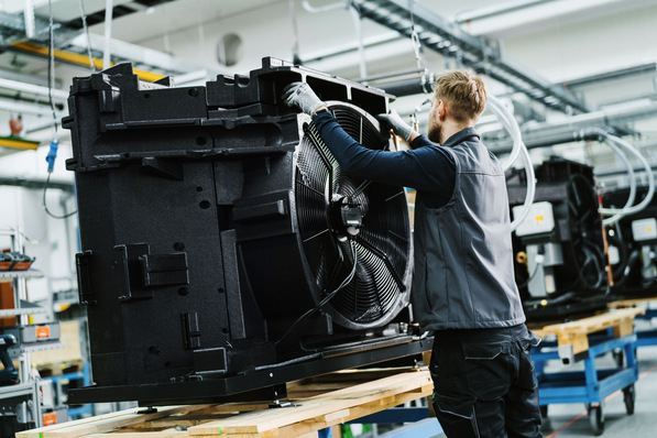 Gerne, hier ein präziser und themenrelevanter Alt-Text für Ihre Zielgruppe: Optimierter Alt-Text: „Facharbeiter montiert eine große Ventilationseinheit einer raumlufttechnischen Anlage in einer Werkhalle – Beispiel für technische Gebäudeausrüstung in der modernen Anlagentechnik.“ Auf Wunsch kann ich noch gezielter auf einzelne Themen oder Bildinhalte eingehen, z. B. Energieeffizienz, Montageprozesse oder branchenspezifische Aspekte. - © Wolf